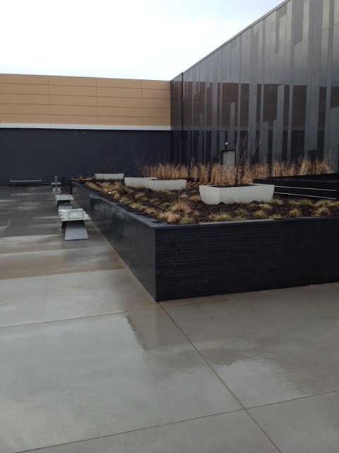 Norstone Lynia Interlocking Tiles in Ebony Basalt color used to clad a commercial landscaping wall as part of a large retail project.